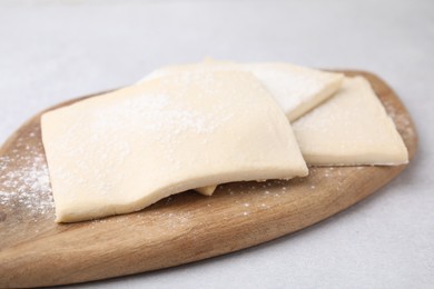 Raw puff pastry dough on white table, closeup