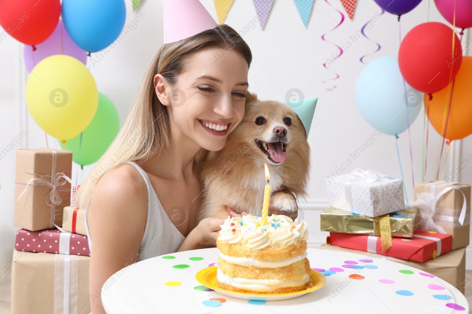 Photo of Happy woman celebrating her pet's birthday in decorated room