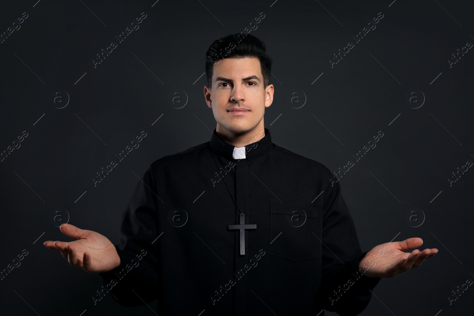 Photo of Priest wearing cassock with clerical collar on black background