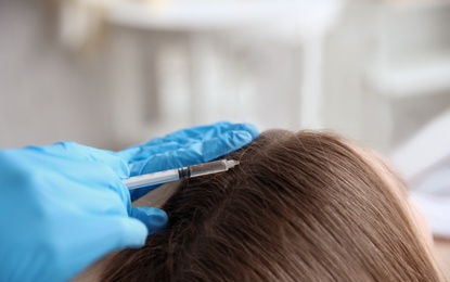 Photo of Young woman with hair loss problem receiving injection in clinic