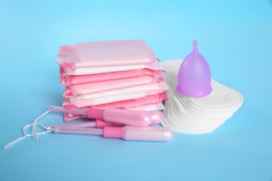 Photo of Menstrual pads and other hygiene products on light blue background