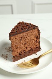Photo of Piece of delicious chocolate truffle cake and fork on white table, closeup