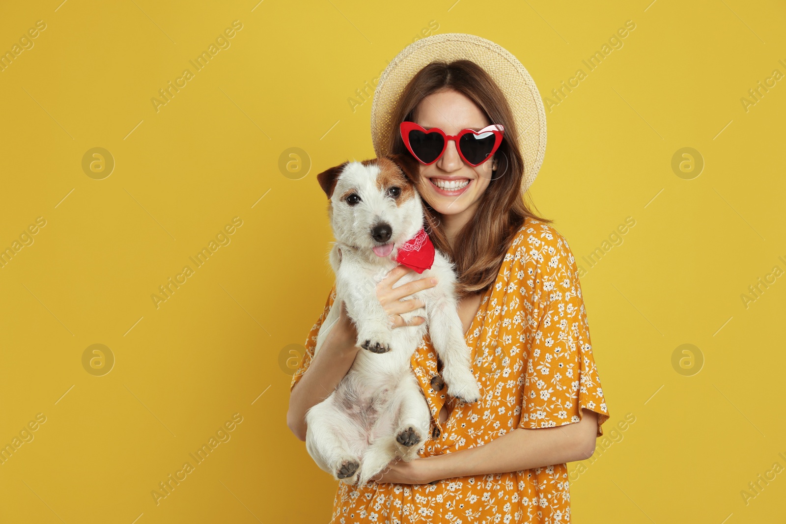 Photo of Young woman with her cute Jack Russell Terrier on yellow background. Lovely pet