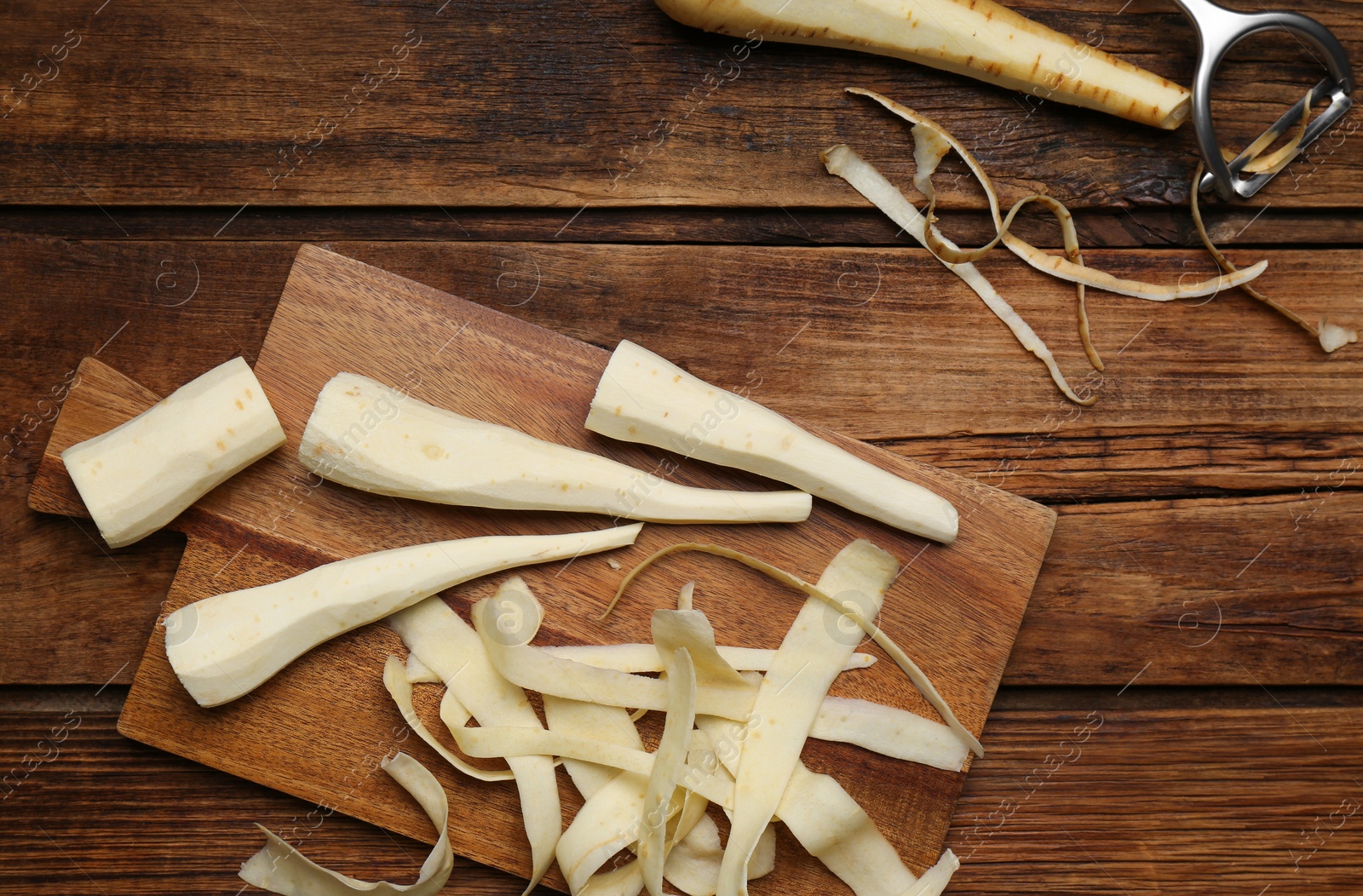 Photo of Peeled fresh parsnips and strips on wooden table, flat lay