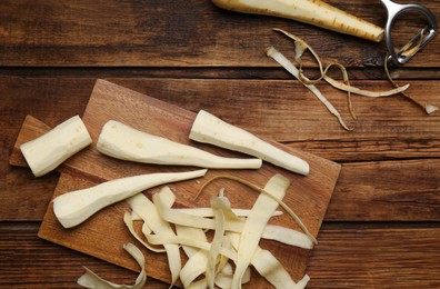 Photo of Peeled fresh parsnips and strips on wooden table, flat lay
