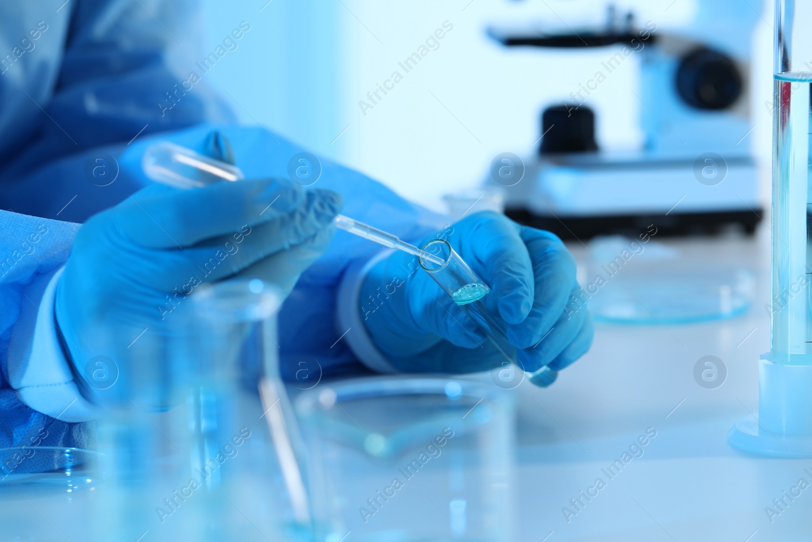 Photo of Scientist dripping sample into test tube in laboratory, closeup. Medical research