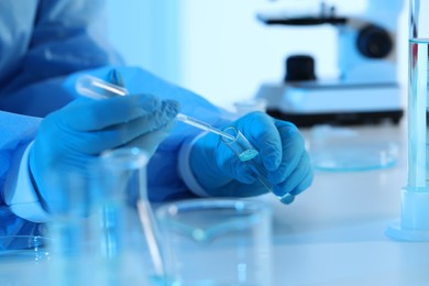 Scientist dripping sample into test tube in laboratory, closeup. Medical research