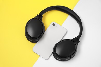 Photo of Modern wireless headphones and smartphone on color background, above view
