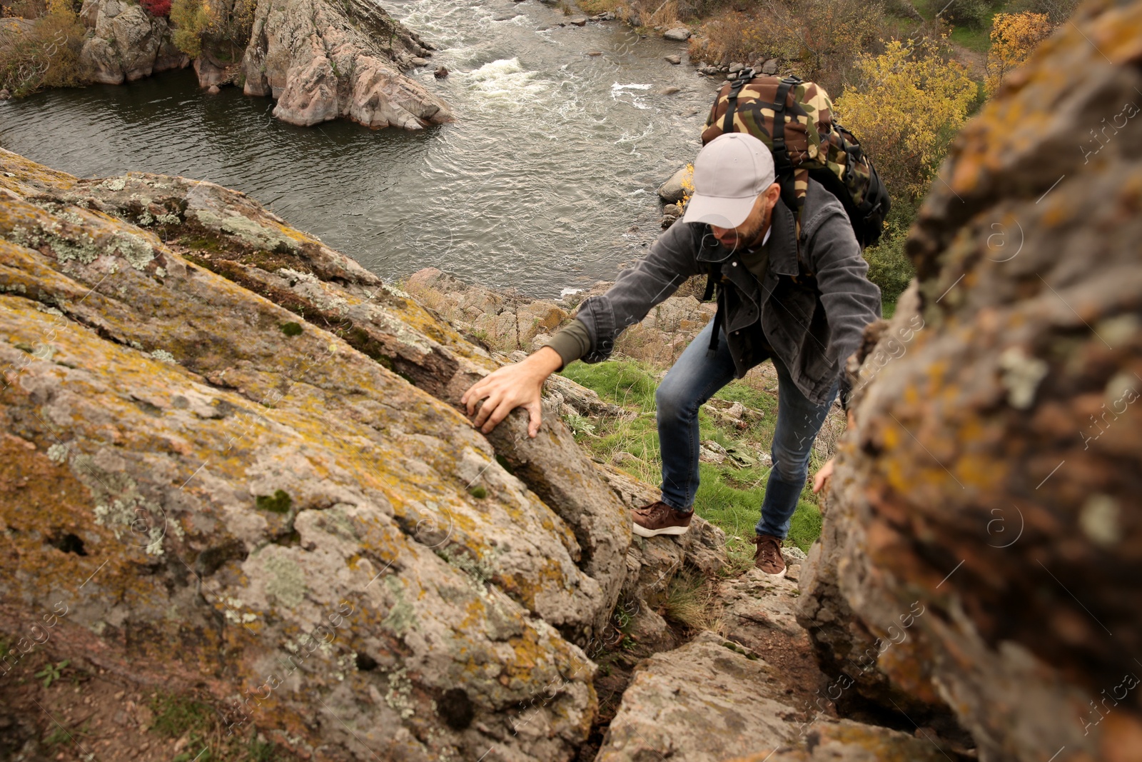 Photo of Hiker with backpack climbing up mountain on autumn day