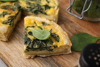 Photo of Piece of delicious pie with spinach on wooden board, closeup