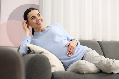 Photo of Happy pregnant woman on sofa at home