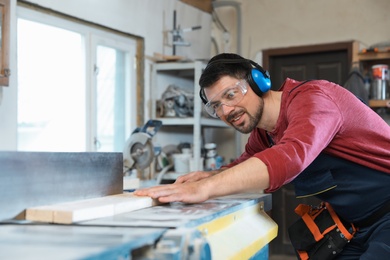 Photo of Mature man using wood working machine at carpentry shop