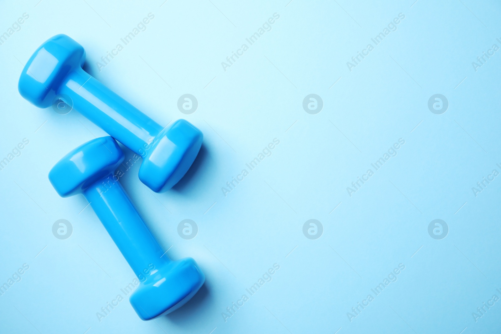 Photo of Bright dumbbells and space for text on color background, flat lay. Home fitness