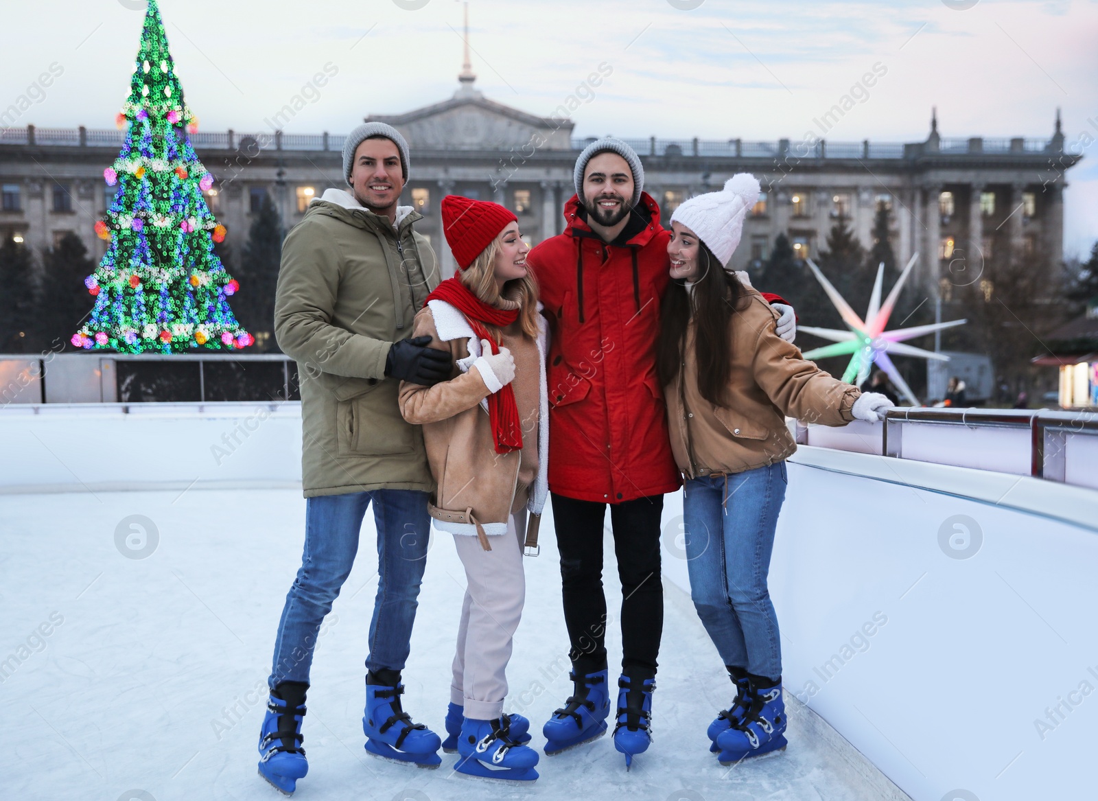 Image of Group of friends near fence at outdoor ice rink