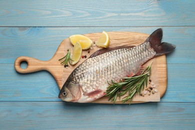 Photo of Fresh raw crucian carp and ingredients on light blue wooden table, top view. River fish