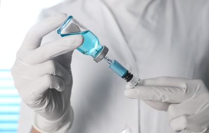 Photo of Doctor filling syringe with vaccine from vial, closeup