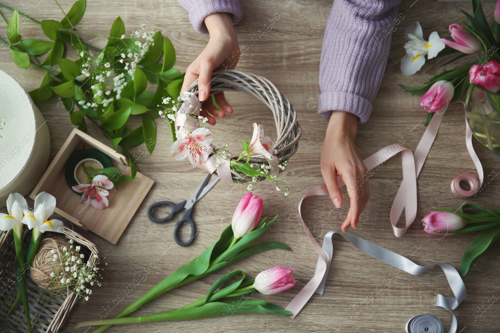 Photo of Female decorator creating beautiful bouquet at table, top view