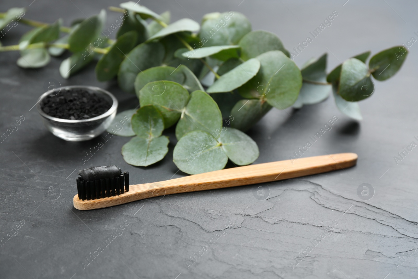 Photo of Bamboo toothbrush with charcoal paste on black stone table