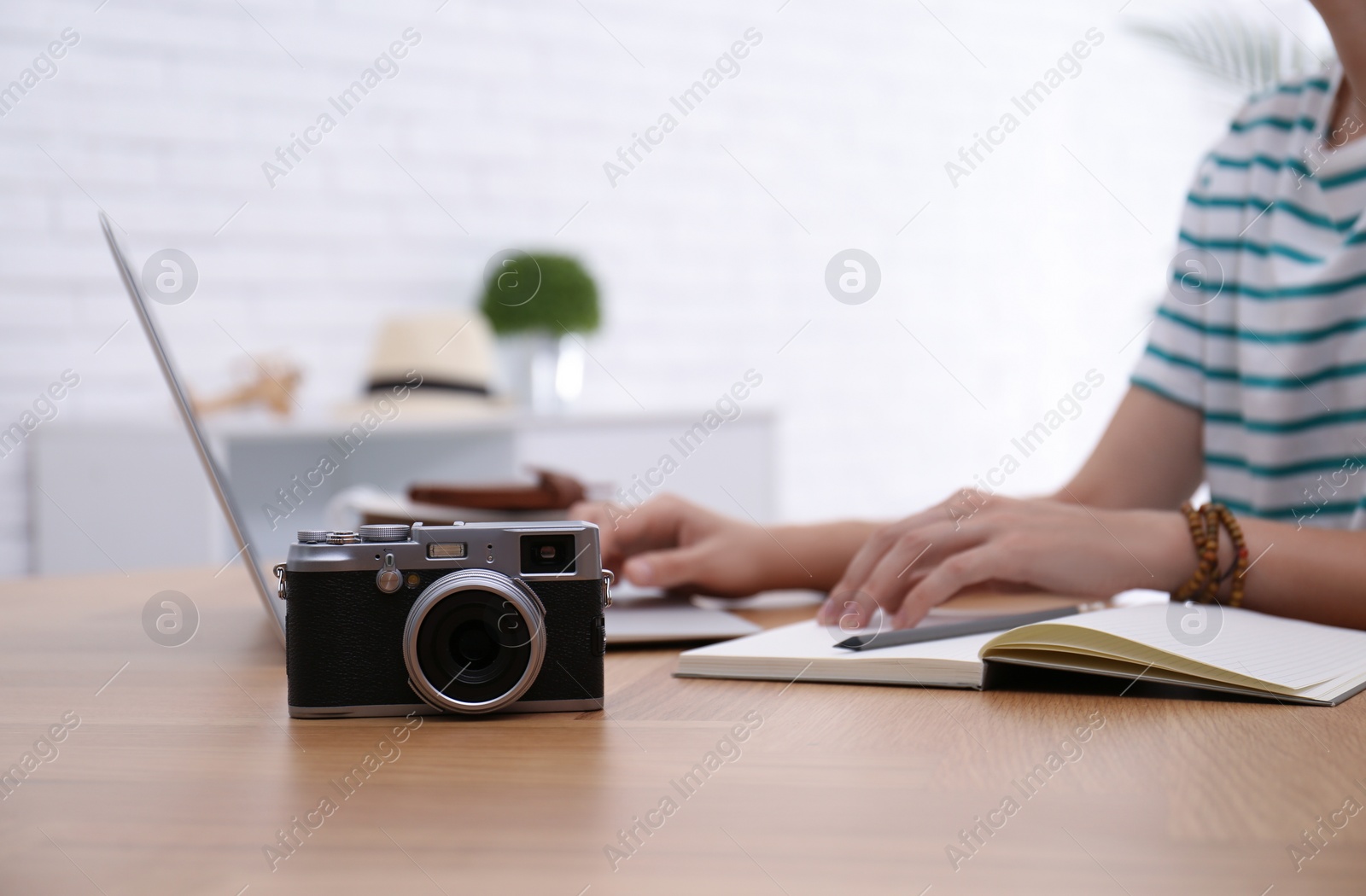 Photo of Woman using laptop to plan trip at wooden table, closeup