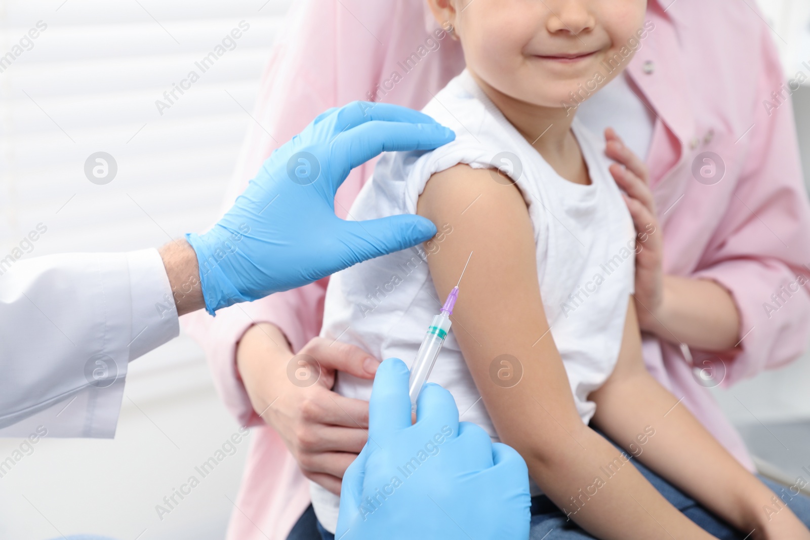 Photo of Children's hepatitis vaccination. Mother with her daughter in clinic. Doctor giving injection to little girl, closeup