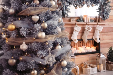 Photo of Christmas tree near decorative fireplace in room, closeup view. Festive interior