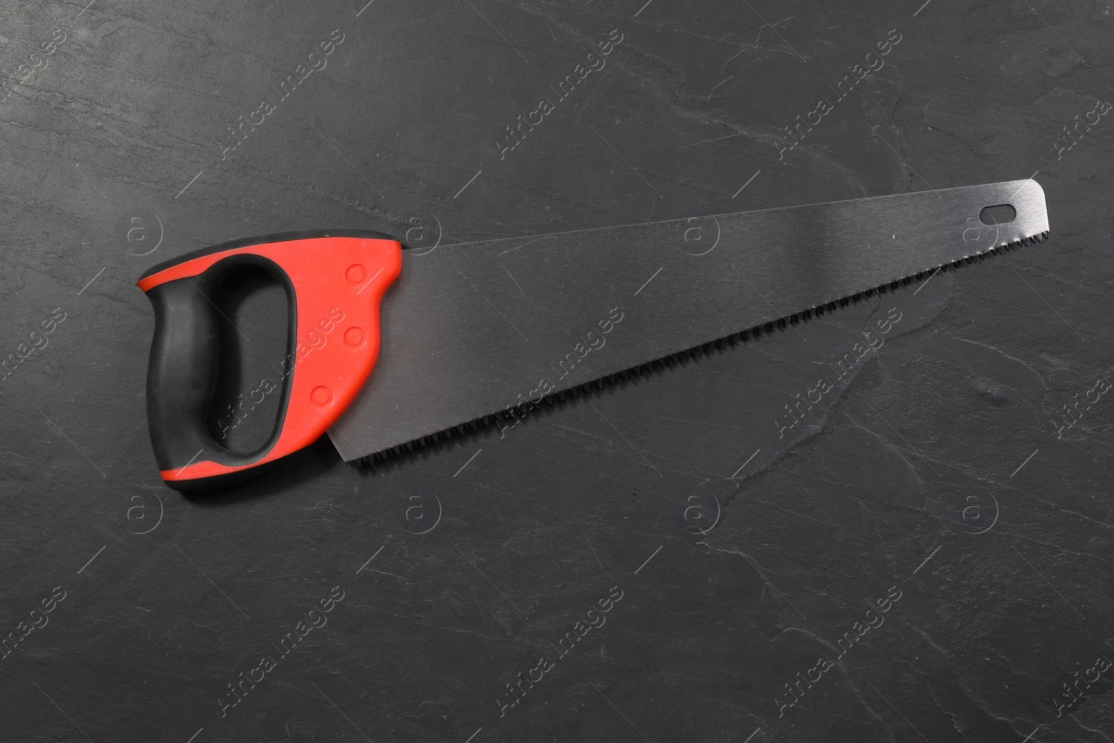 Photo of Saw with colorful handle on black textured background, top view