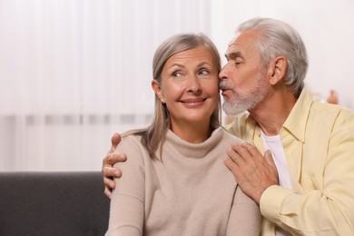Photo of Senior man kissing his beloved woman at home, space for text