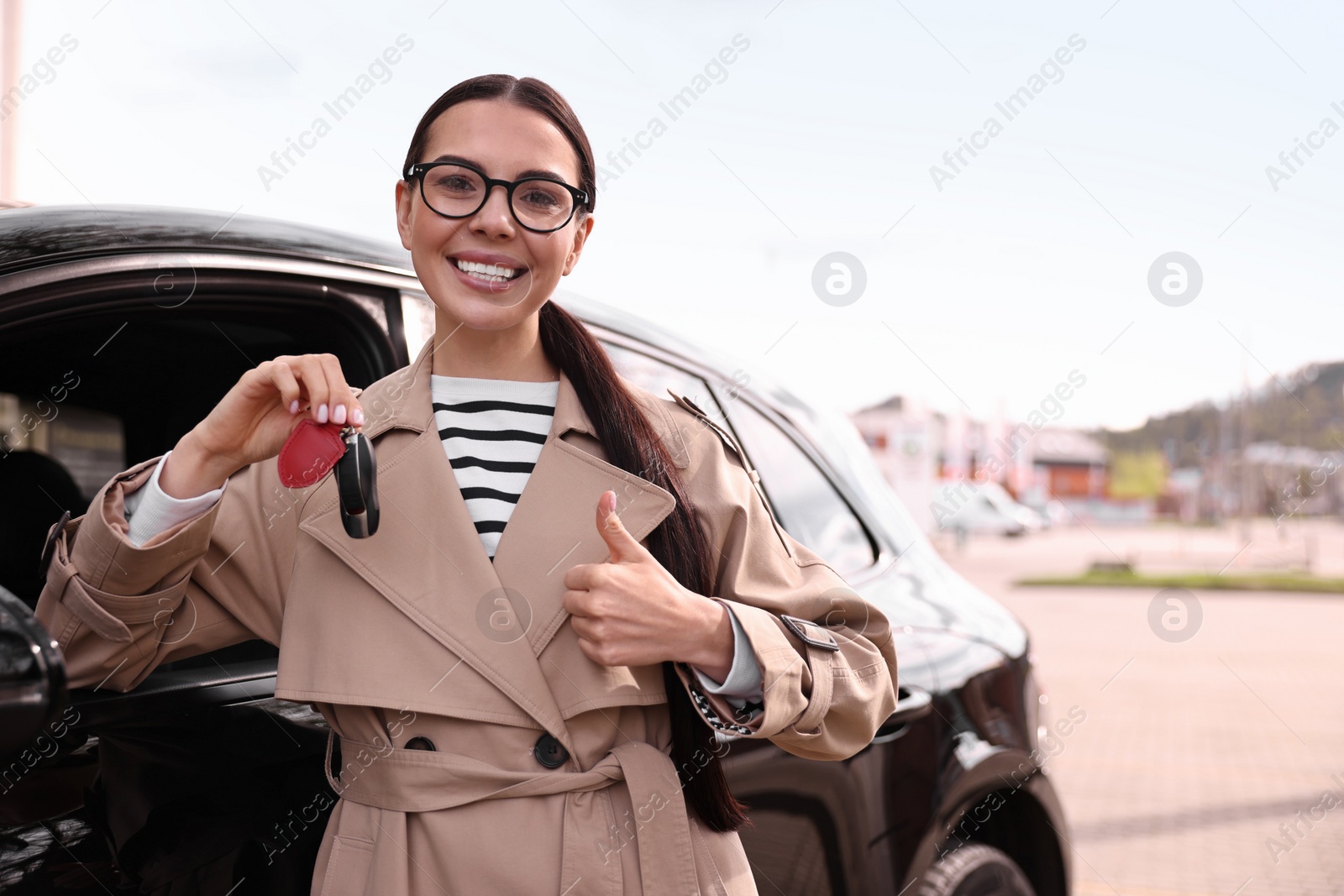 Photo of Woman holding car flip key near her vehicle outdoors