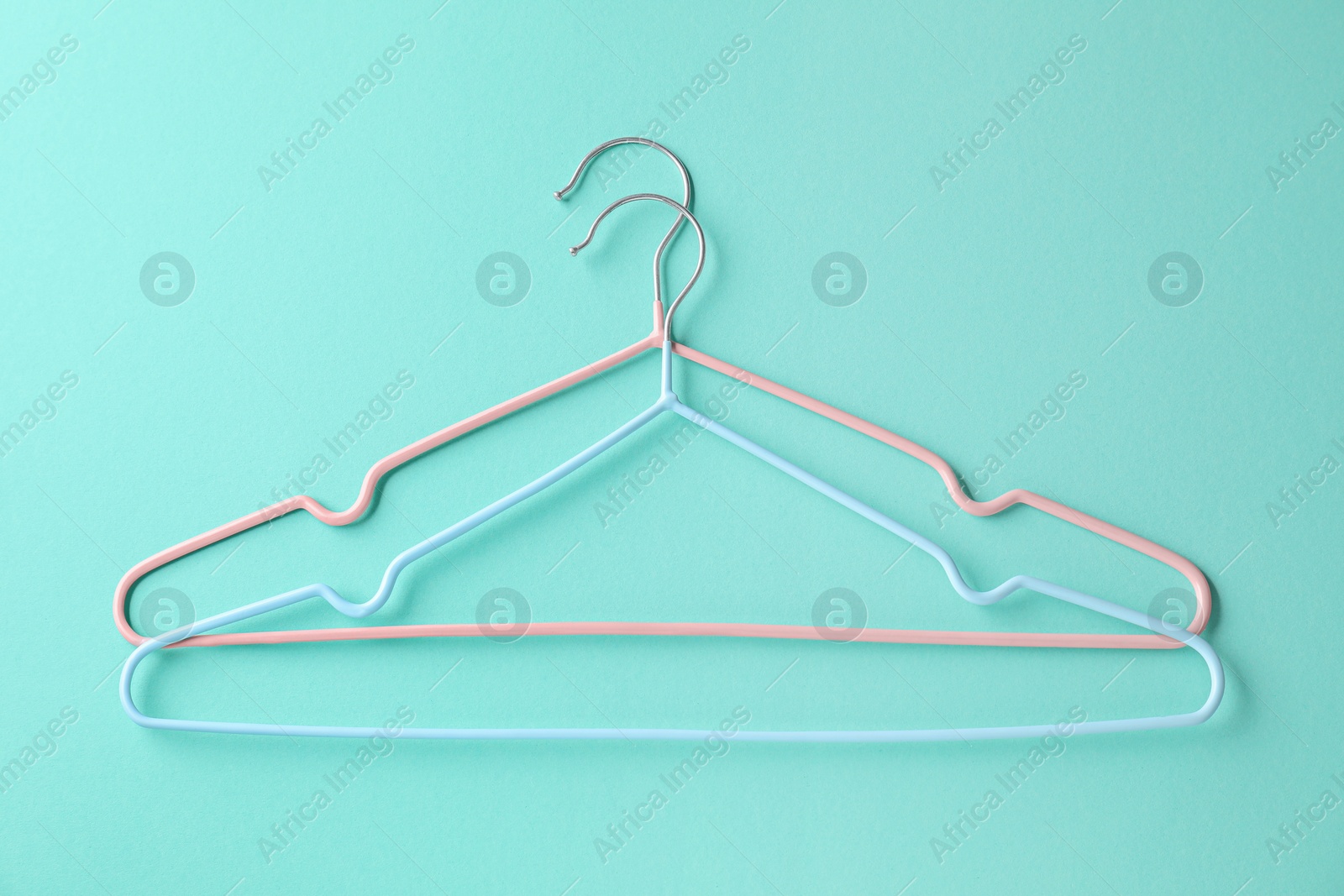 Photo of Two hangers on light blue background, top view