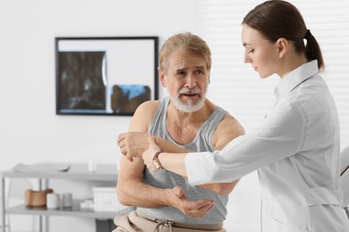 Orthopedist examining patient with injured arm in clinic