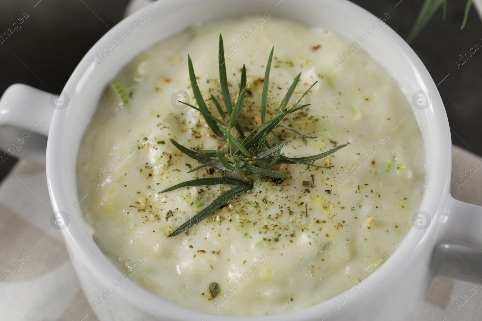 Photo of Delicious cream soup with tarragon, spices and potato in bowl, closeup