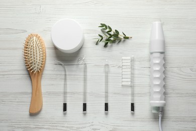 Photo of Flat lay composition with darsonval and different nozzles on white wooden table