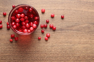 Photo of Tasty cranberry juice in glass and fresh berries on wooden table, top view. Space for text