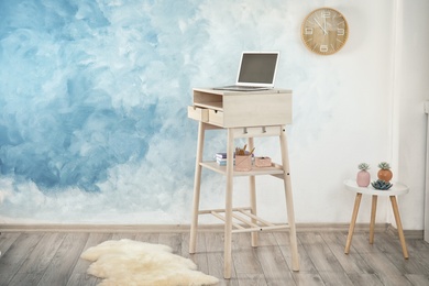 High wooden table with laptop as stand up workplace in modern interior