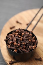 Photo of Aromatic cloves in scoop on table, closeup