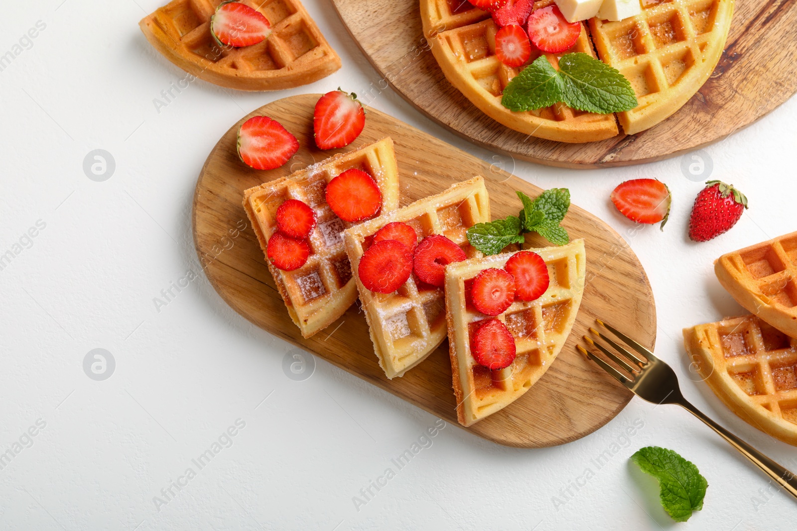 Photo of Tasty Belgian waffles with strawberries, mint and fork on white table, flat lay