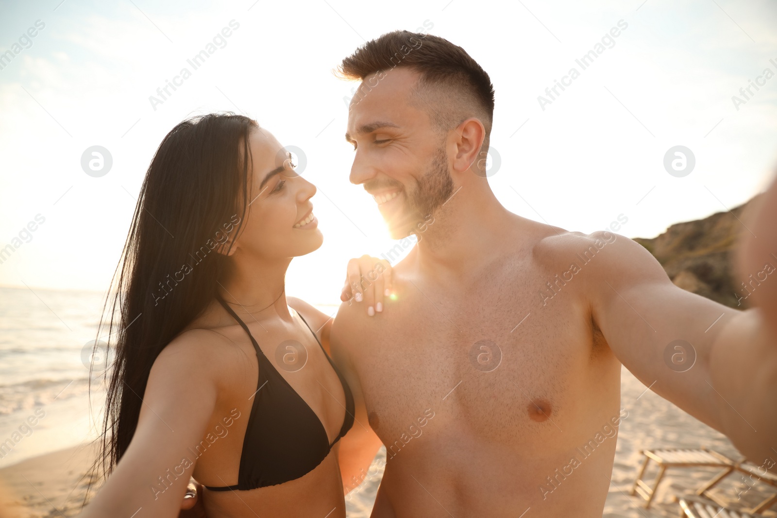 Photo of Happy young couple taking selfie on beach at sunset