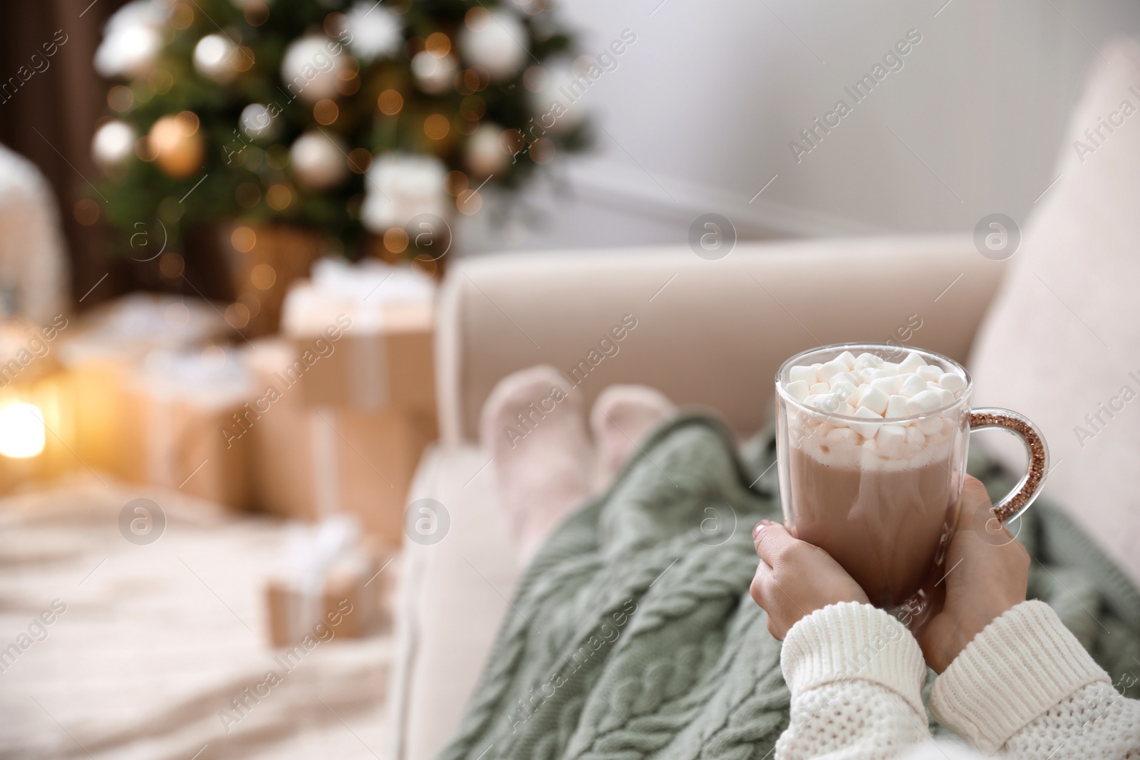 Photo of Woman with delicious hot drink wrapped in plaid on sofa at home, closeup. Space for text