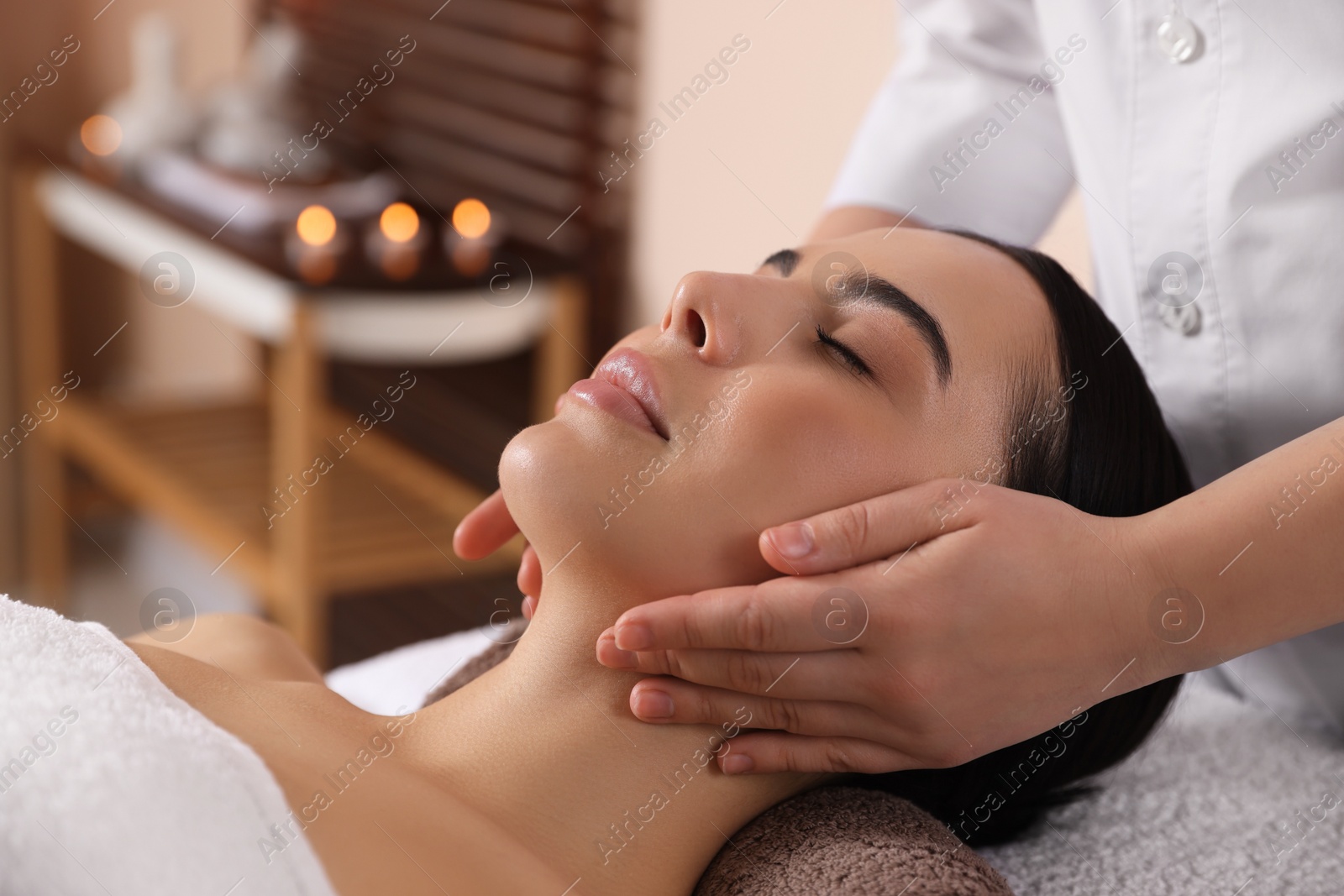 Photo of Young woman enjoying professional massage in spa salon, closeup