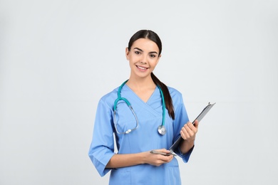 Photo of Portrait of medical assistant with stethoscope and clipboard on light background
