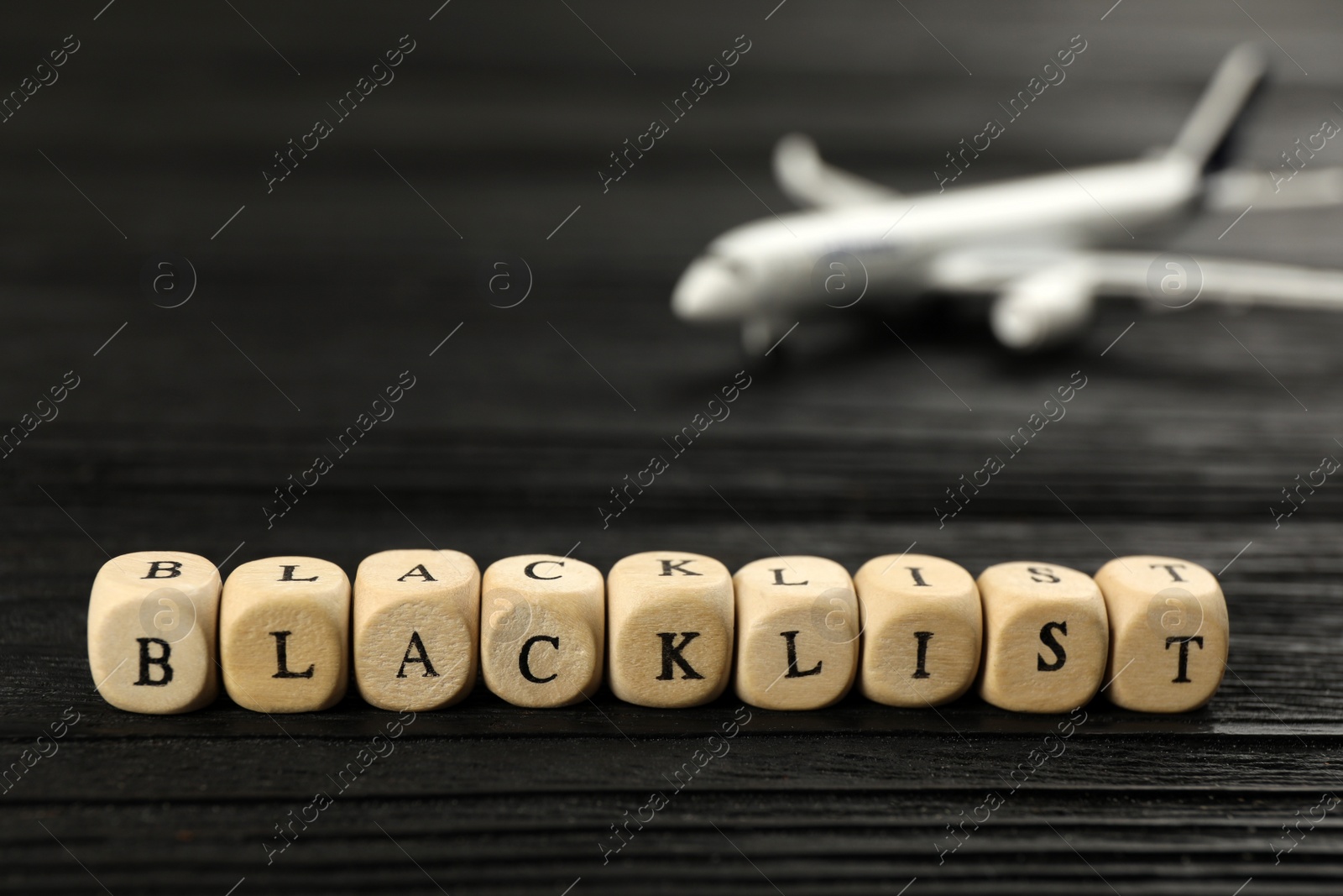 Photo of Cubes with word Blacklist on black wooden table, closeup