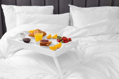 Photo of Tray with delicious breakfast on bed, space for text