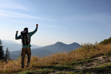 Photo of Tourist with backpack in mountains on sunny day, back view. Space for text