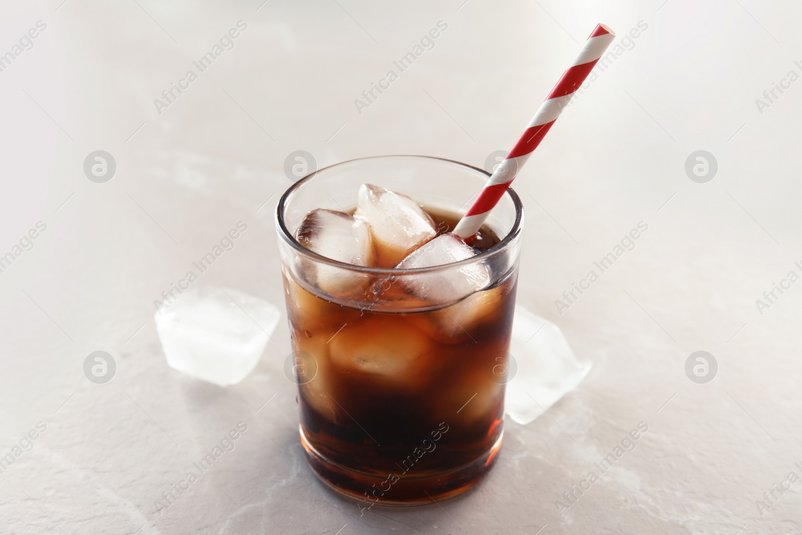 Photo of Glass of refreshing cola with ice on grey background
