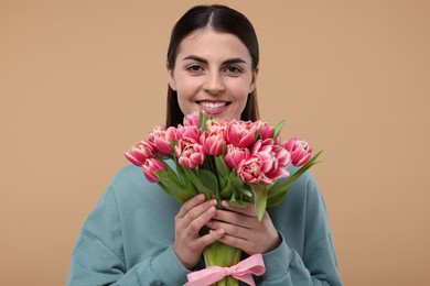 Photo of Happy young woman with beautiful bouquet on beige background