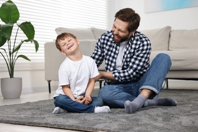 Happy dad and son having fun on carpet at home