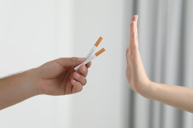Photo of Stop smoking concept. Woman refusing cigarettes on blurred background, closeup