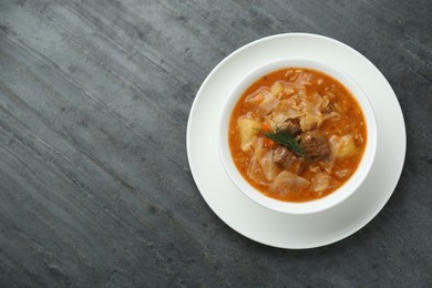 Tasty cabbage soup with meat, carrot and dill on black table, top view. Space for text