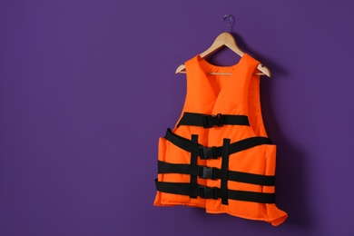 Photo of Orange life jacket on violet background. Space for text