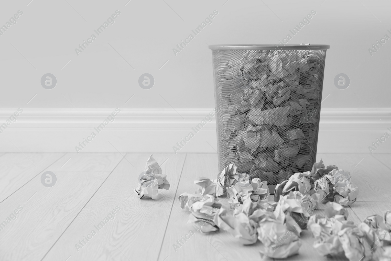 Photo of Metal bin and crumpled paper against light wall, space for text